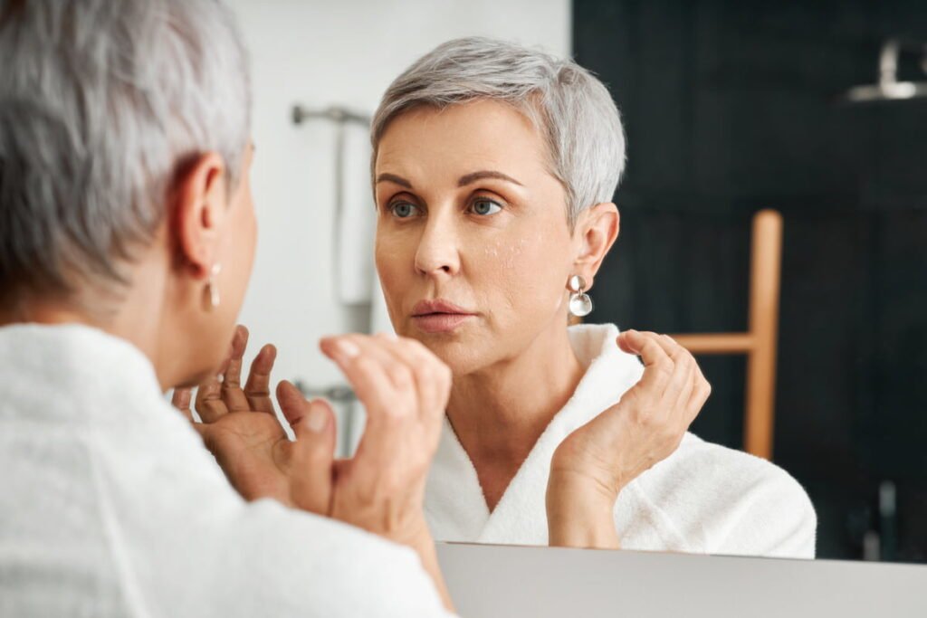 Senior woman looking at skin in mirror