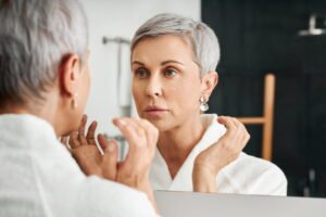 Senior woman looking at skin in mirror