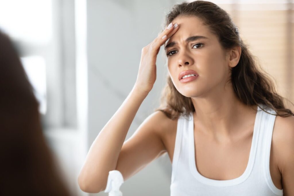 Young woman looking in mirror at wrinkles after a discounted Botox treatment