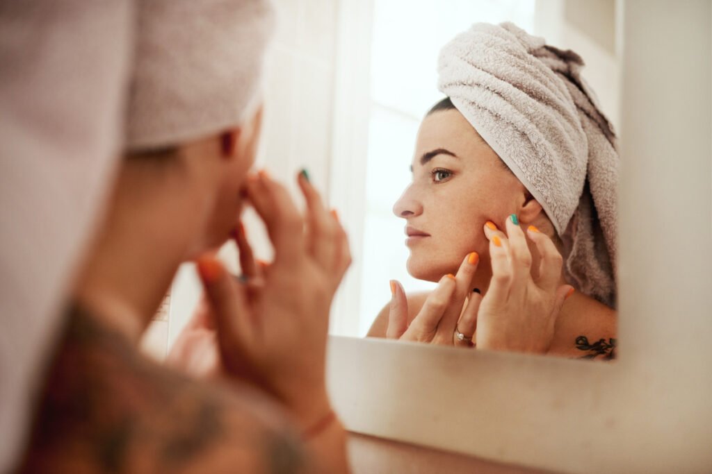 Young woman looking up close at skin in the bathroom mirror