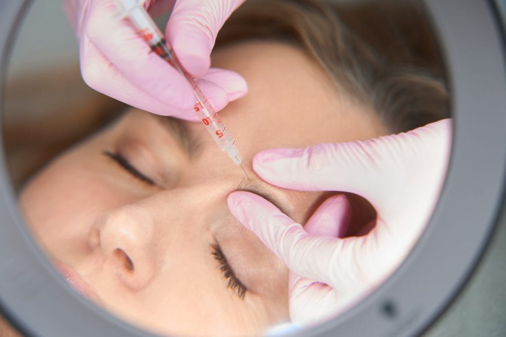 Close up of woman getting Botox injections around her eyebrow