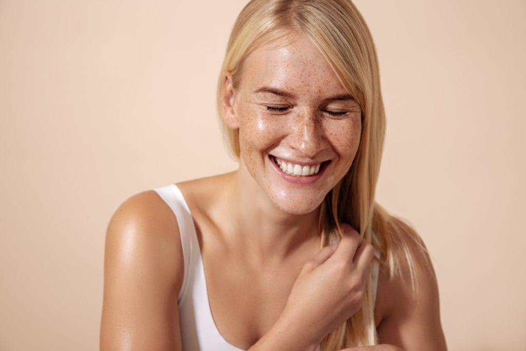 Freckled blonde woman with glowing skin smiling