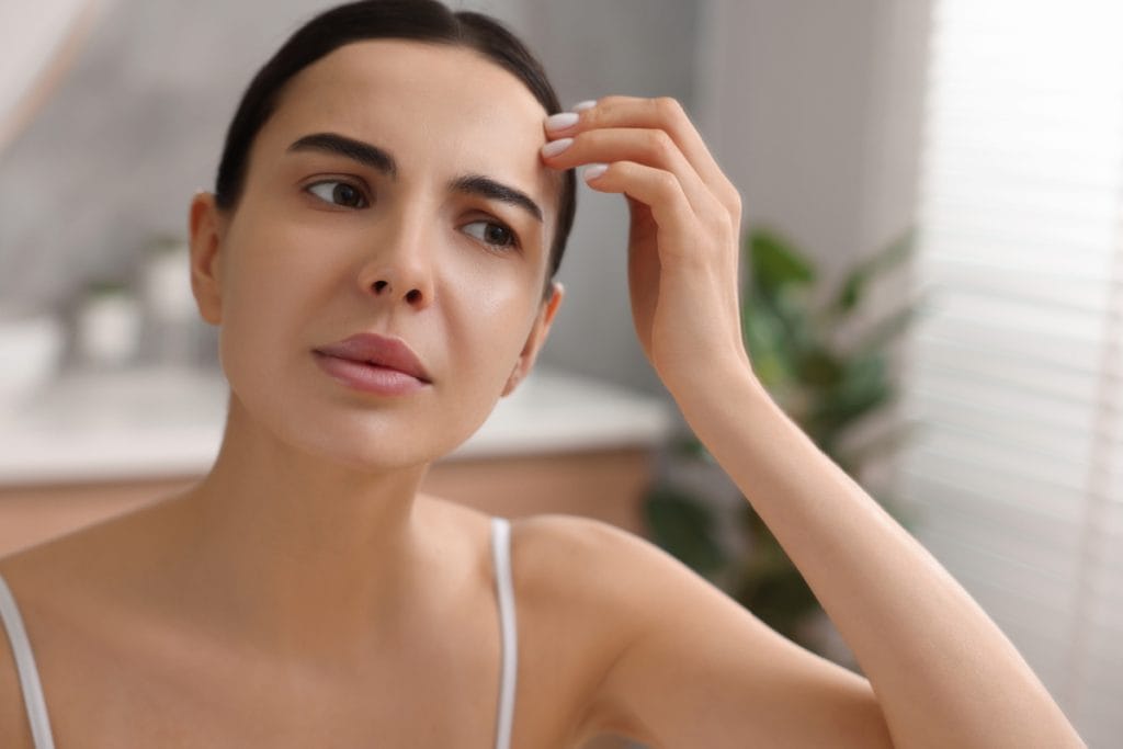 Woman frowning at twitching brows after Botox injections